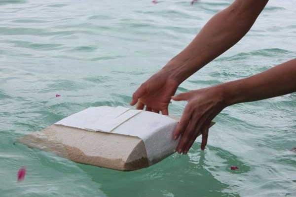 A water-soluble eco burial pillow being gently placed into the sea